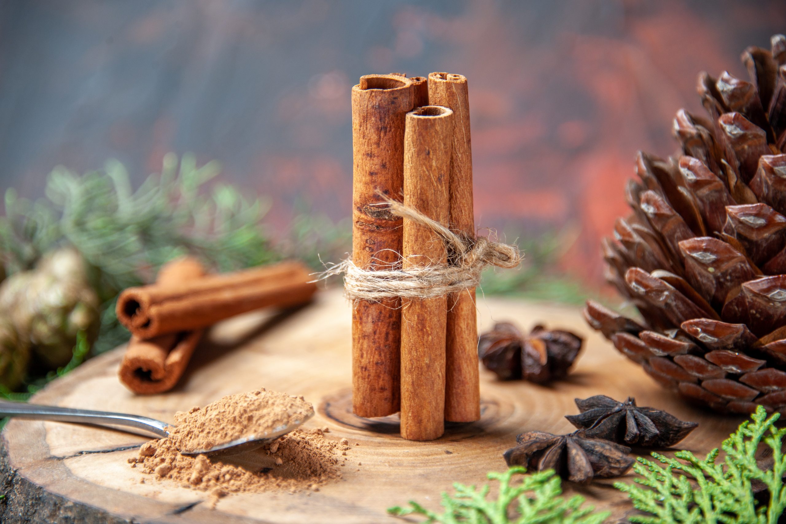 front-view-cinnamon-sticks-cinnamon-powders-pinecone-anises-wood-board-dark