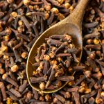 top view dried cloves with a wooden spoon
